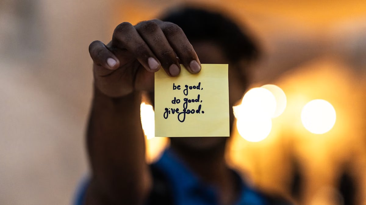 A person holds a sticky note with an encouraging message in Dubai.